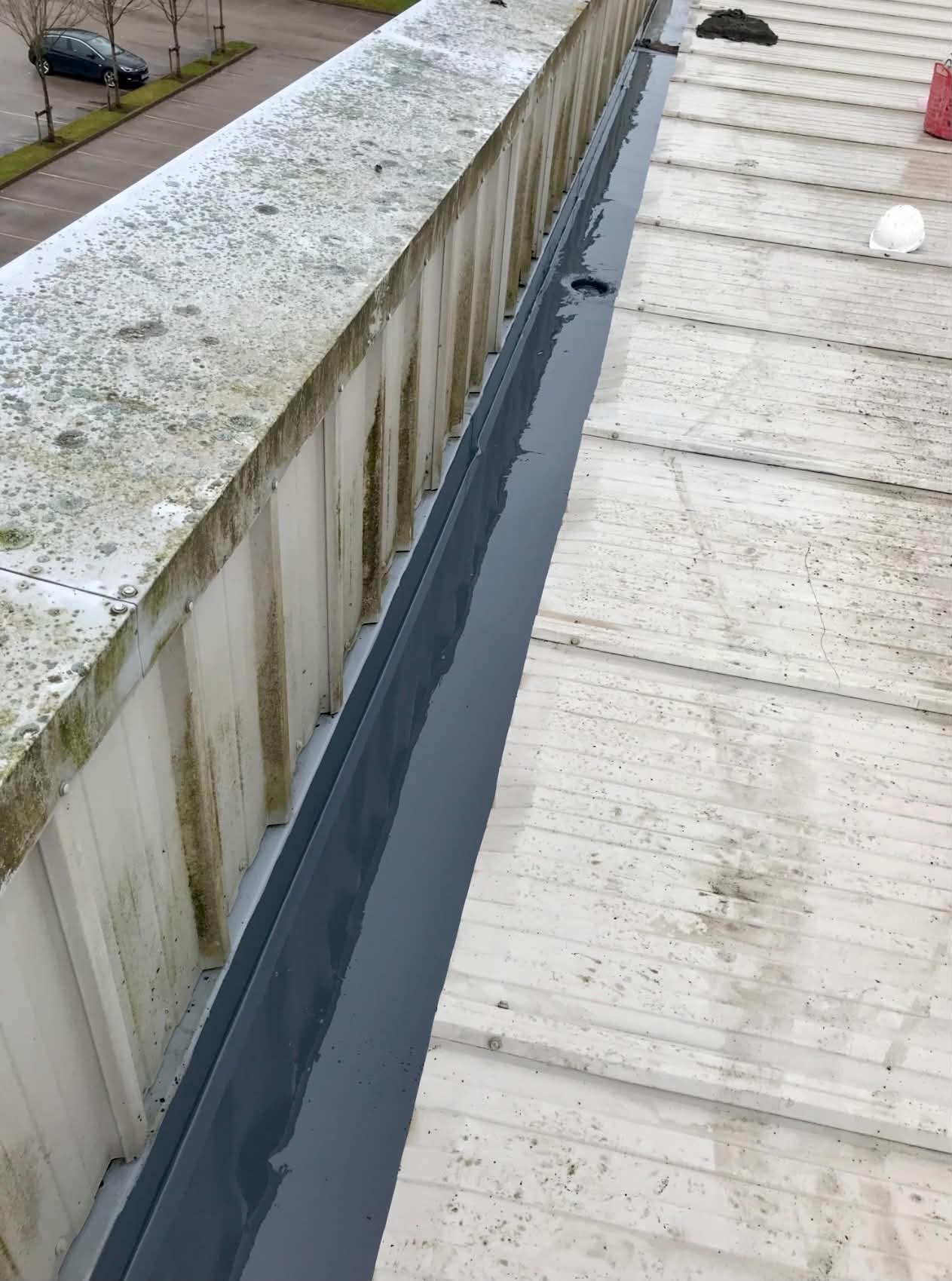 Parapet gutter lined with grey liquid applied waterproofing on a commercial building